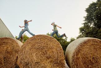 Kids leaping across hay bales by Portraits of Modern Dairy courtesy of Unsplash.